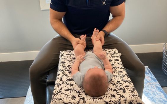 Pediatric chiropractor gently adjusting an infant on a treatment table