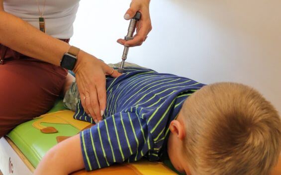 Pediatric chiropractor providing gentle back adjustment to a child